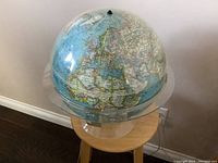 Photo showing entire light up globe on transparent stand with visible on/off toggle on top surface.