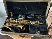 Alto saxophone inside hard shell case with mouthpiece, neck strap, and box of La Voz reeds