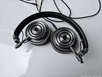 Over-ear metal circular headphones with black leather padded headband and wired connection
