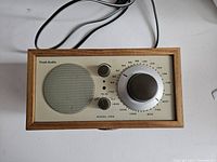 Front view showing wooden case, speaker grille, tuning dial, and control knobs.