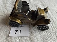 Side profile photo of the coin bank showing antique car design with brass accents and black base.