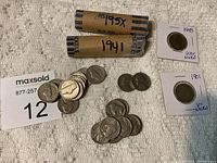 Photo showing rolls of nickels labeled 1941 and 195x, loose nickels of various ages including older Buffalo nickels, and cardboard holders for 1943 War Nickel and 1901 Liberty Nickel.