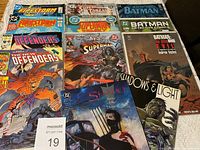 Top view of 12 comic books spread on flat surface showing front covers featuring various superhero titles.