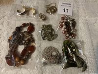Overview of assorted costume jewelry including necklaces, bracelets, earrings, and brooches on fabric background