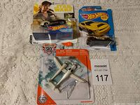 Four collectible items: three Hot Wheels cars in packaging and one Matchbox Sky Busters airplane model, all unopened.