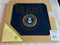 Front view of genuine bonded leather scrapbook in packaging. Blue leather with gold embossed Air Force emblem and text on cover.