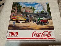 Front view of the sealed Coca-Cola 1000-piece puzzle box showing the vintage delivery scene with a steam locomotive and classic vehicles.