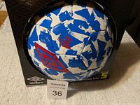 Photo showing front view of new Umbro size 5 soccer ball in original black box with blue and white brushstroke panels and red Umbro logo.