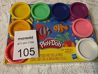 Top-down view of 8 Play-Doh containers on original Play-Doh packaging showing colorful lids and ocean print underneath.