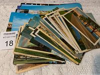 Photo showing a spread of vintage postcards with varied scenic views including beaches and roads, fanned out on a surface.