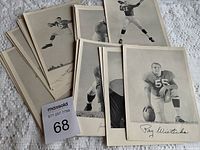 Replica football photos showing a collection of approximately sixteen black and white vintage style football player photos with printed player names, some photos stacked and others displayed in front.