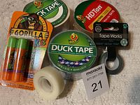 Photo showing multiple rolls of Duck Tape, HD Tan tape, Gorilla Glue Kids glue sticks, and Tape Works clear tape.