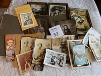 Overview of vintage photos and portraits, some framed, others loose, arranged on fabric surface