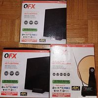 Three boxed QFX HDTV antennas placed on floor, showing front of boxes with branding and features.