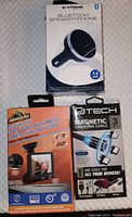 Front view of all three boxed car accessories: Bluetooth speaker phone, magnetic charging cable, and dual dash camera.