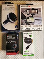 Four boxed items including Bluetooth speaker phone, mirror mount phone holder, FM transmitter charger, and micro USB cable laid out side by side.