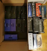 Top-down view showing 19 headphones in packaging from brands including 2Boom, Fisher, Coby, and Bass Max. Packaging shows wear and tear.
