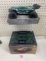 Side view of the 1/18 scale stadium R/C truck on a display stand with original packaging box beneath it.