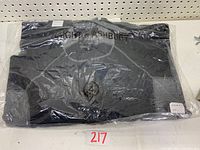 Folded black Haight Ashbury long sleeve shirt in plastic packaging, front view showing zipper area and neckline with brand label visible.