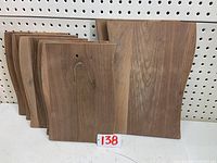Photo shows group of black walnut medium and large size unfinished cutting boards stacked together with visible natural wood grain and smooth finish. Includes board with drilled hole for hanging.