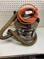 Filter Queen vacuum with attached flexible hose and coiled orange power cord on top.