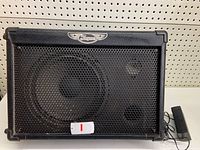 Front view of black Traynor TM50 guitar amplifier with metal grille, Traynor logo, and power supply cable.