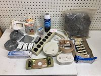 Wide view showing entire lot with outlets, power bar, detectors, electrical boxes, grout sealer, screws, hose/wire supports, and coaxial wall plates.