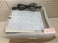 LED grow light panel with power cable coiled, viewed from the front showing LED array and metal heat sink surface.