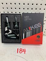 Two ALIKEE LED H7 headlight bulbs inside black foam tray next to their branded black and red box labeled +300%