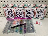 Photo showing four sheets of butterfly nail art stickers and four plastic containers with various nail decorations and a pink application tool