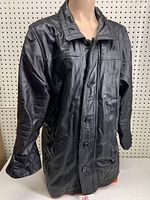 Front view of the black leather men's coat showing button closure, collar, and overall condition.