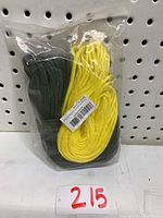 Two paracord ropes, yellow and dark green, coiled and sealed in clear plastic packaging against a pegboard background.
