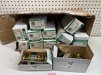 Box of multiple Nuklor passage door handle sets with brass finish, including handles and latches.