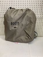 Carrying/storage bag for the ROOTS inflatable mattress made of light brown fabric with ROOTS Outdoor logo.