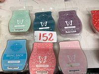 Six Scentsy wax scent bars in various colors including blue, teal, purple, red, pink, and turquoise with visible scent names on packaging.