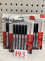 Three unopened packs of Sharpie Ultra Fine markers, each pack containing five black markers, arranged against a pegboard background with inventory number 143.
