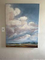 Full front view of the canvas painting on a wall showing the blue sky with puffy clouds and an abstract landscape below.