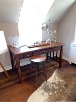View of the desk from front and left side showing three drawers on the front, vertical slat design on the side panels, and medium brown wood finish.