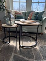 Both modern nesting tables shown together with the lantern on the smaller table, coffee book on larger table, sunroom setting.