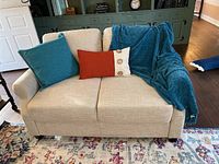 Front view of loveseat with accent pillows and throw