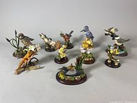 Group photo showing all 10 handcrafted bird figurines by COUNTRY ARTISTS, arranged in a semi-circle, highlighting variety in species, bases, and colors.