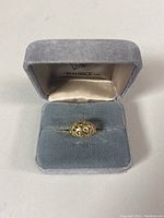 Ring in blue velour ring box with visible pierced gold design.