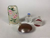 Photo of all items: perfume bottle, leather topped flask, French vase, and etched glass scent bottle arranged together