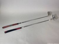 Two Wilson golf putters side by side, showing full length with grips and shafts.