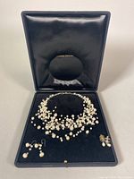 Three floating baroque freshwater pearl necklaces and two pairs of earrings displayed in black velvet jewelry case.