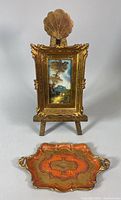 Front view of easel displaying framed painting with tray placed in front