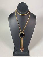 Full view of the vintage brass necklace with large black stone displayed on a black mannequin form.