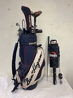 Full view of Ben Hogan golf bag with clubs including labeled club heads and visible clubs inside bag, along with Alien Golf equipment on right side