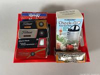 Image showing various golf balls and a golf sweet spot finder on a red tray.