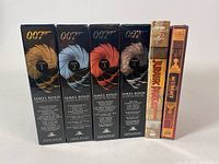 Front view of five black and gold James Bond DVD boxes and two additional DVDs (Jurassic Park and The Mummy) showing titles and slipcases.